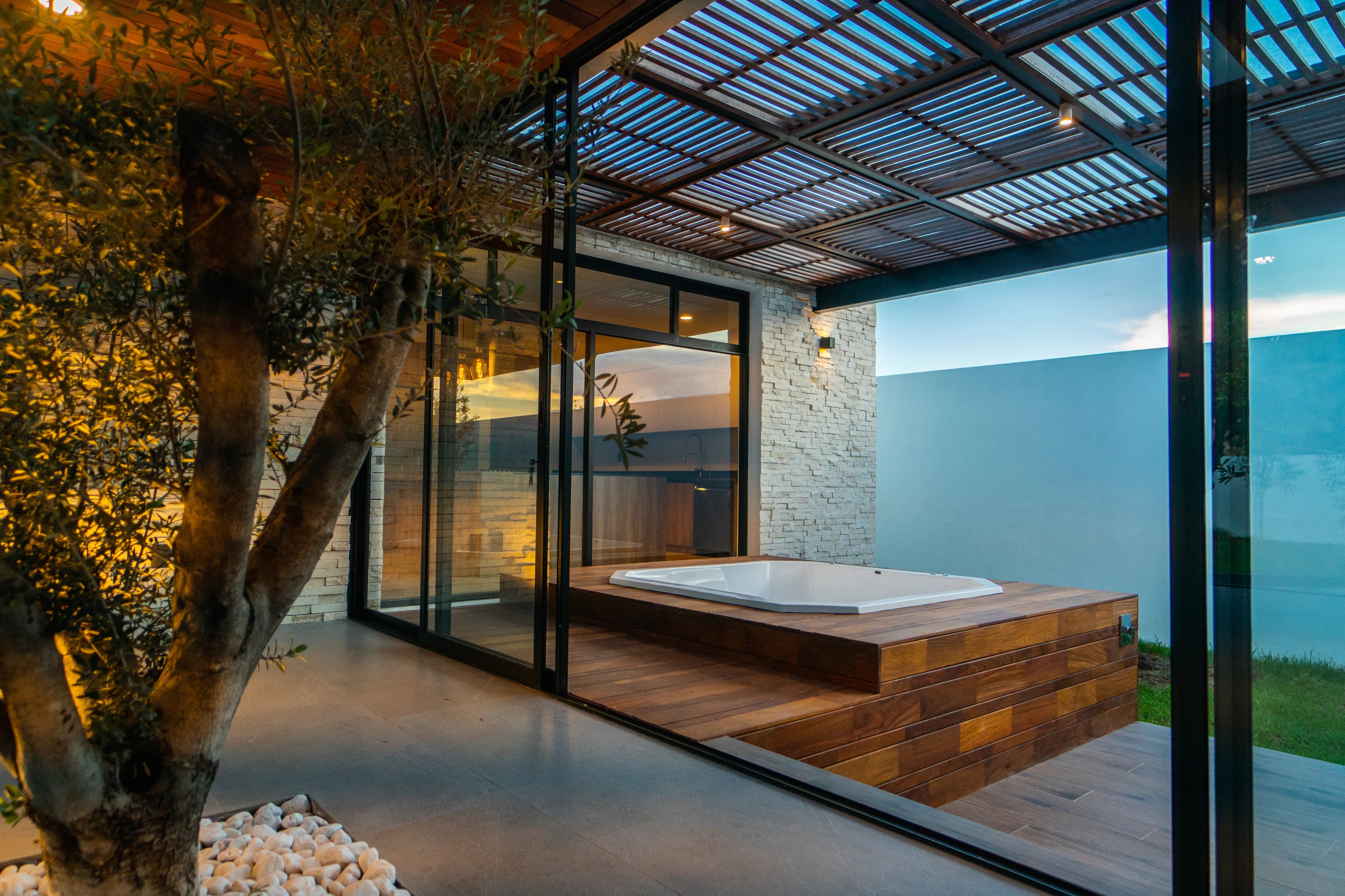 Patio de Casa Cointzio con jacuzzi de madera bajo una pérgola metálica