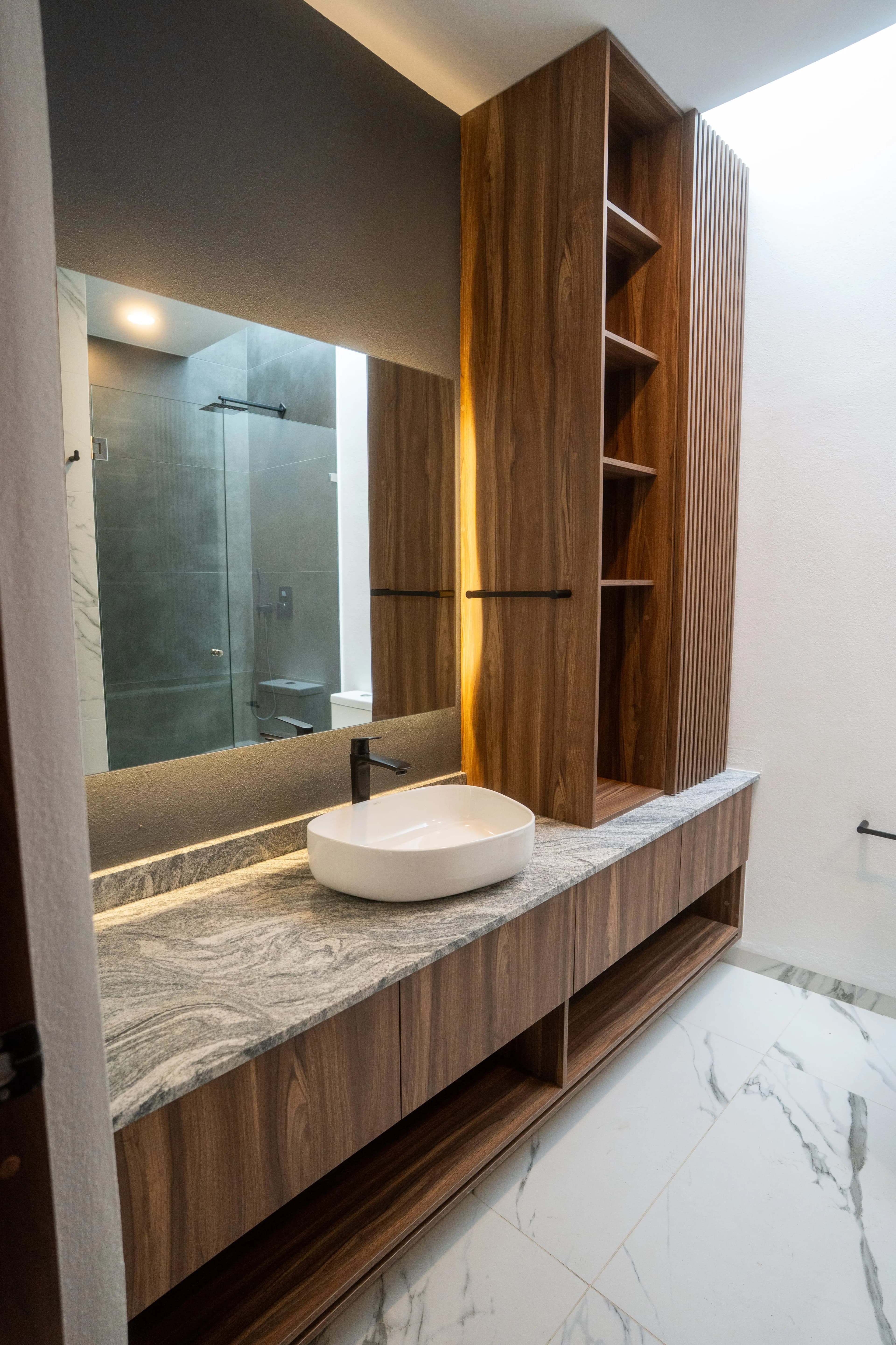 Baño de Casa Colibrí con lavabo de mármol y torre de madera empotrada