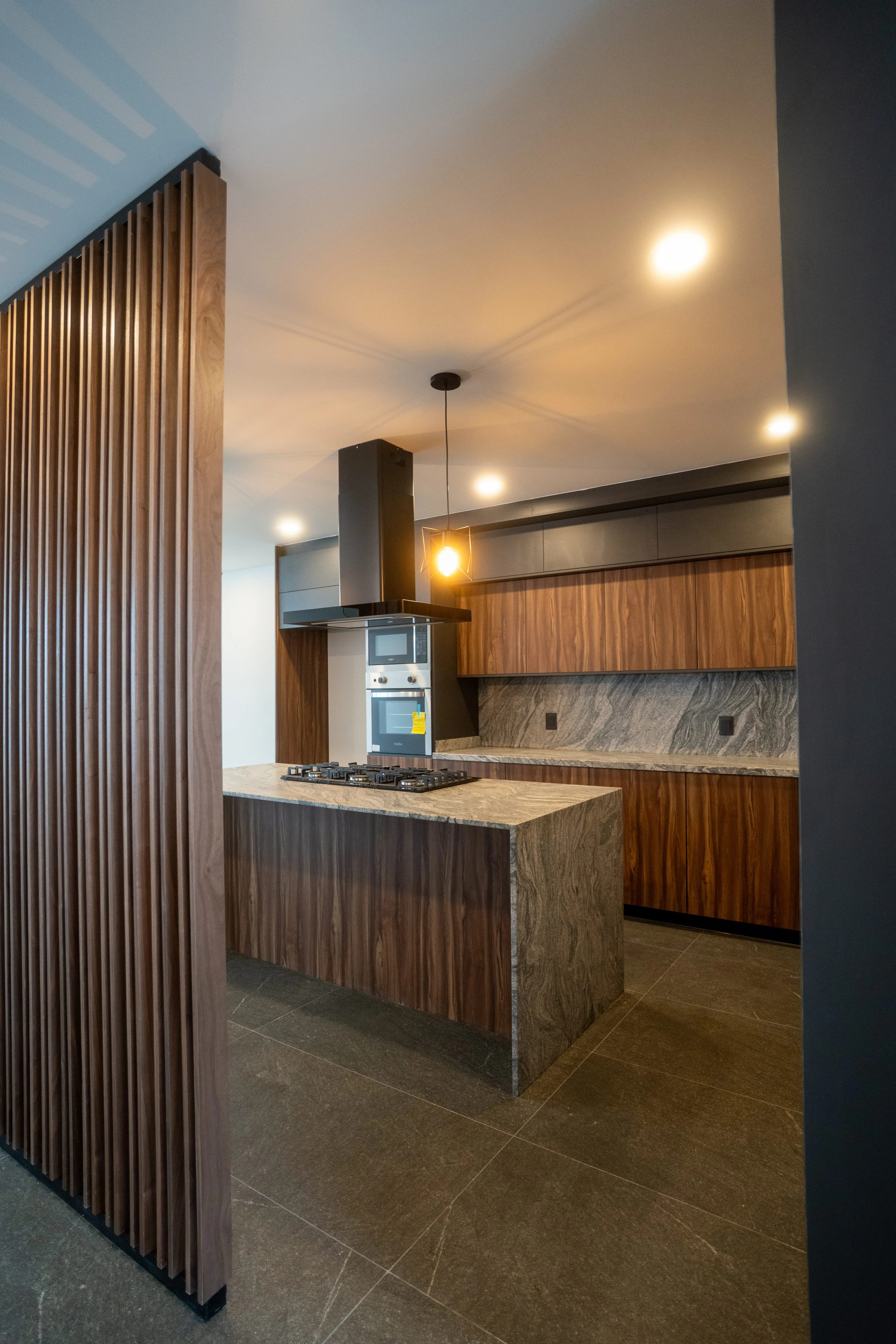 Cocina de Casa Colibrí tras una celosía de madera, con isla de concreto