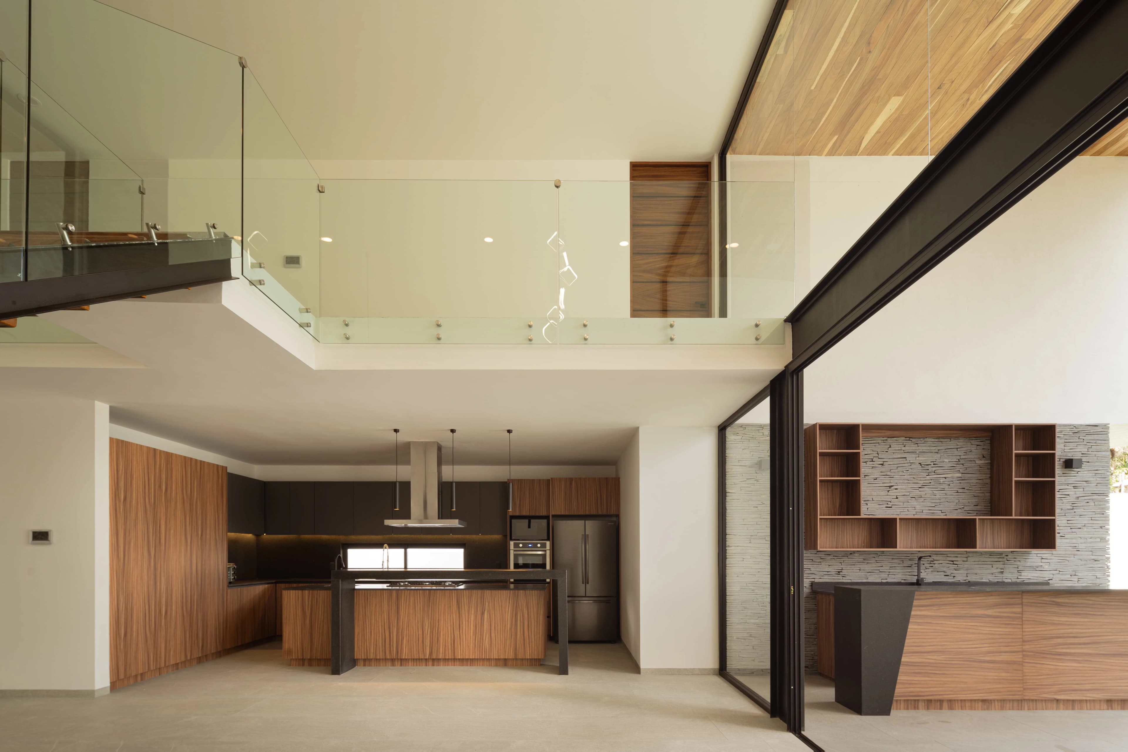 Cocina de Casa del Ángel abierta a la doble altura, con isla y carpintería de madera