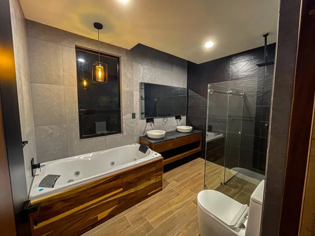 Baño de Casa Dos Pinos con tina de hidromasaje, dos lavabos y regadera de cristal