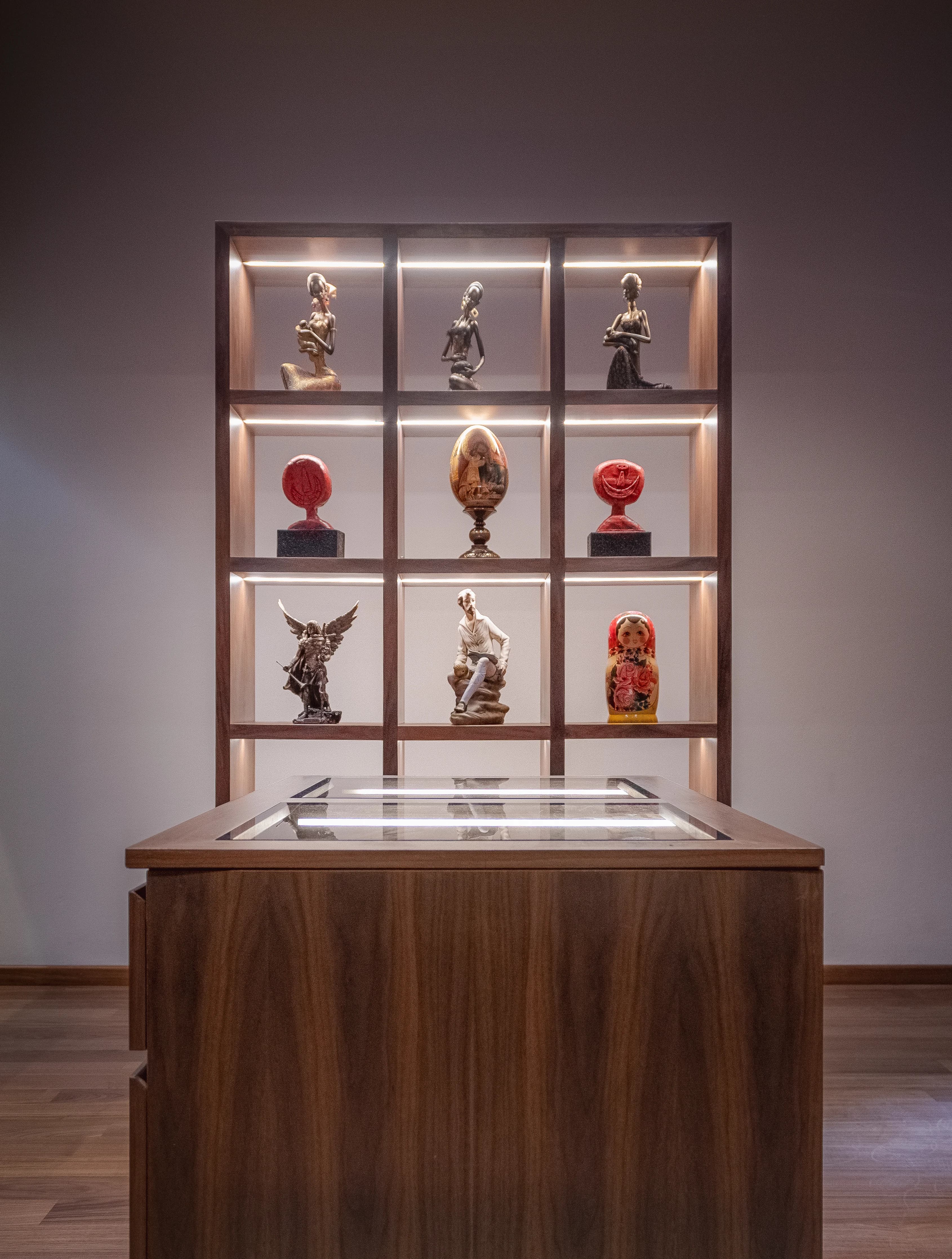Vitrina empotrada e iluminada de L&C, con una colección de figuras sobre mueble de madera