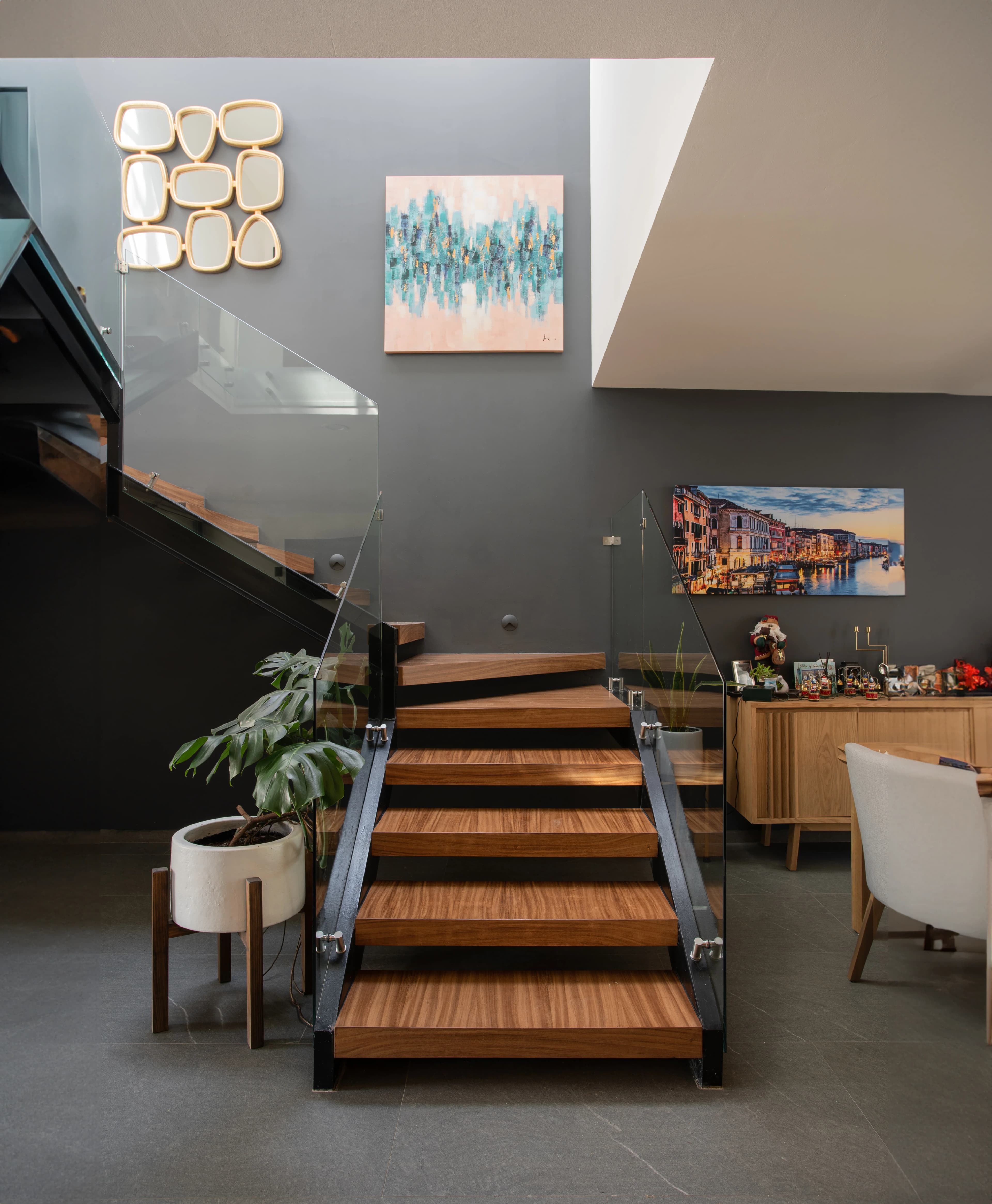 Escalera de madera de Casa Zorros sobre muro gris, con la sala al fondo
