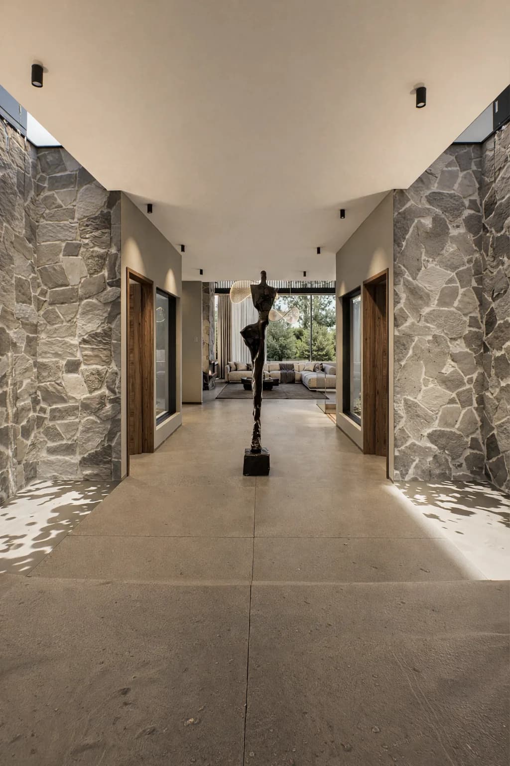 Vestíbulo de acceso de la Residencia Jade, con muros de piedra y escultura central