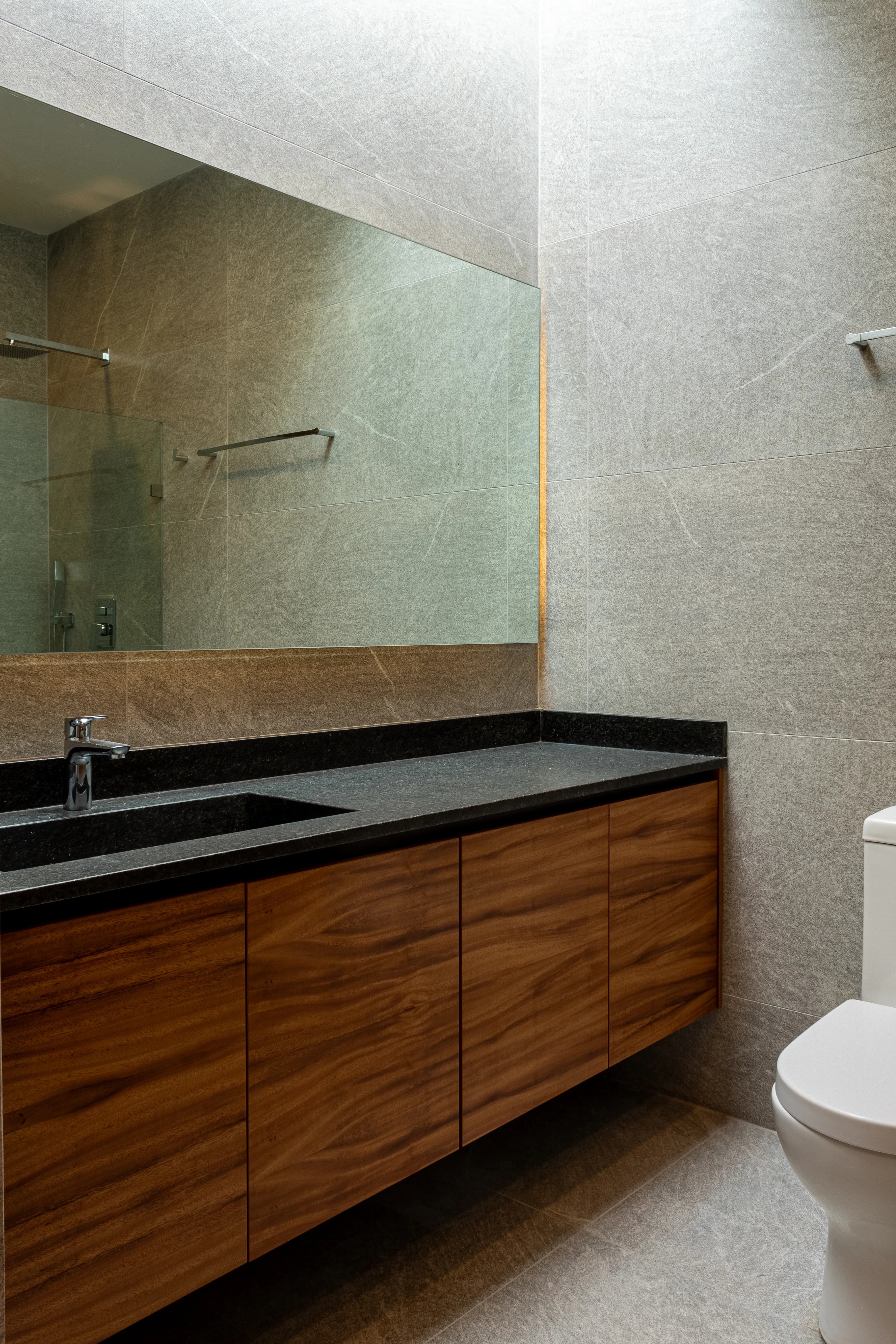 Baño de Casa Encinos con dos lavabos sobre mueble de madera y muro de piedra